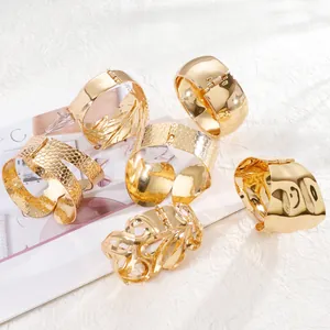 Detailed close-up of various gold wide cuff bracelets with hammered and smooth textures