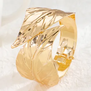 Detailed close-up of a wide gold leaf-shaped cuff bracelet with a glossy metallic finish