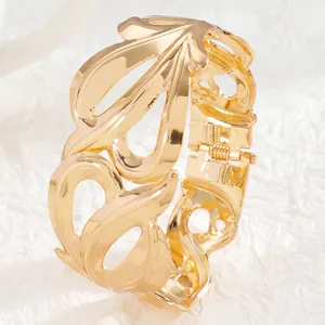 Detailed close-up of a wide gold cuff bracelet featuring vintage hollow floral patterns