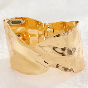 Macro view of wide irregular gold bangle featuring a hinged clasp and organic ripples