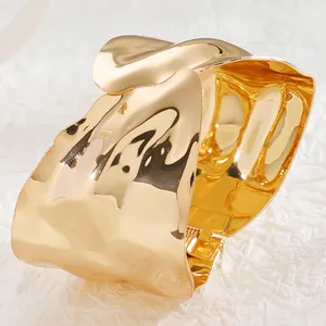 Close-up of golden irregular wavy textured wide cuff bracelet with mirror finish