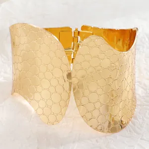 Detailed close-up of wide gold cuff bracelet featuring irregular hammered texture and hinge