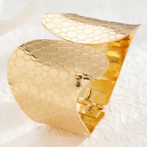 Detail of wide gold cuff bracelet featuring embossed bubble texture and spring hinge