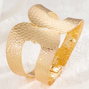 Detailed macro view of wide gold cuff bracelet featuring textured finish and heart cutout