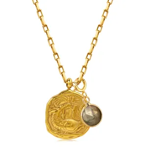 Close-up of 18k gold zodiac necklace with embossed round pendant and gemstone charm