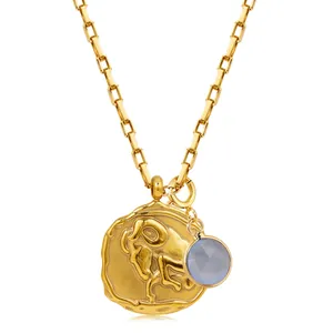 Detailed macro view of 18k gold paperclip chain with Aries coin and blue gemstone