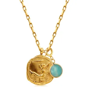 Detail of 18k gold chain with mermaid coin pendant and round blue gemstone charm