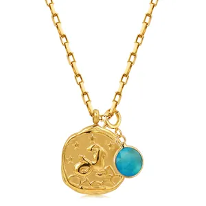 Macro view of Capricorn constellation coin and blue gemstone on 18k gold chain necklace