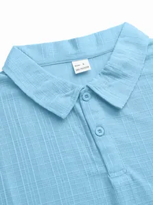 Close-up of light blue polo shirt collar featuring waffle texture and two buttons