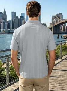 Rear view of men's grey textured short sleeve polo shirt with a city skyline background