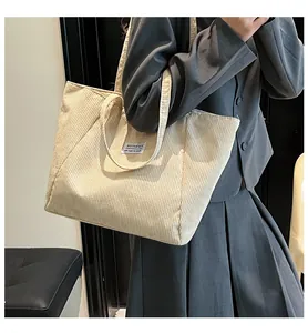 Close-up detail of beige corduroy tote bag showing fashion label and textured fabric