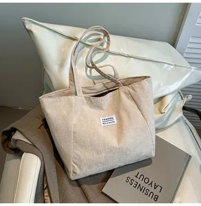 Detail of cream corduroy tote bag showing ribbed texture and fashion logo patch