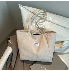 Detail view of beige corduroy tote bag texture with fashion label on a vintage chair