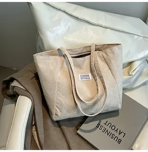 Detail view of the beige corduroy tote bag showing ribbed texture and fashion label