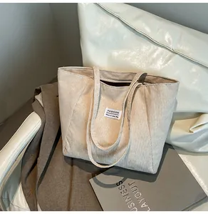 Detail of cream corduroy tote bag featuring ribbed texture and stylish fashion logo label