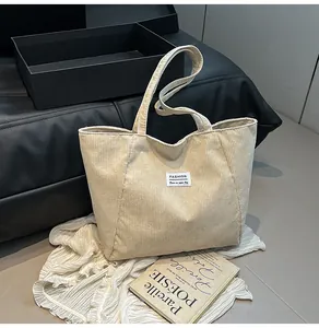 Detail of off-white corduroy tote bag featuring vertical stripes and fashion textile label