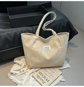 Close-up of beige corduroy tote bag featuring vertical texture and a fashion label