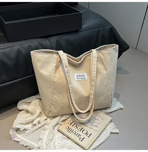 Close-up of beige corduroy tote bag featuring vertical texture and Fashion woven label