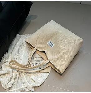 Detailed close-up showing the ribbed corduroy fabric texture of the beige tote bag
