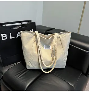 Detailed view of beige corduroy tote bag texture with minimalist woven label detail