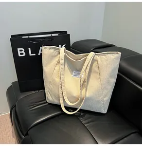 Detailed view of beige corduroy tote bag texture with fashion label on black leather sofa
