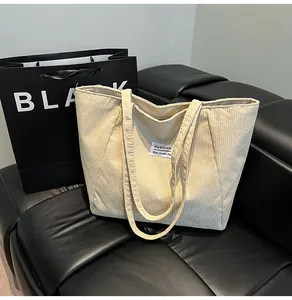 Detail of beige corduroy tote bag showing striped texture on a black leather sofa