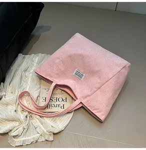 Detail view of pink corduroy tote bag with Fashion label on a textured background