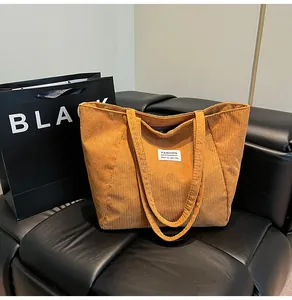 Close-up of mustard yellow corduroy tote bag showing ribbed texture and fashion label