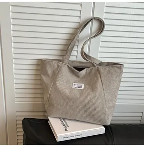 Detail of light khaki corduroy tote bag with vertical stripes and fashion label tag