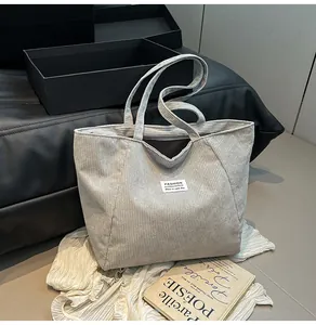 Detailed shot of corduroy tote bag with white letter patch on grey ribbed fabric