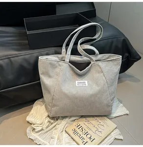 Detail view of grey corduroy tote bag showing the fabric texture and fashion label