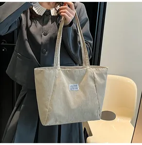 Close-up of beige corduroy tote bag with fashion label and textured ribbing detail