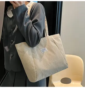 Detail of corduroy tote bag featuring a white Fashion label and soft ribbed texture
