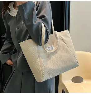 Close-up of off-white corduroy tote bag featuring vertical texture and Fashion label