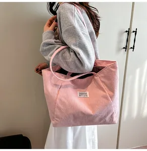 Close-up of pink corduroy tote bag with fashion label and textured vertical stripes