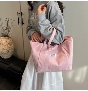 Detail shot of light pink corduroy tote bag featuring a white fashion logo patch