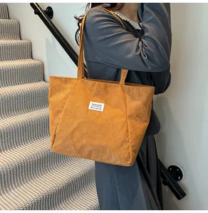 Detail of a large yellow corduroy tote bag with Fashion label carried on the shoulder