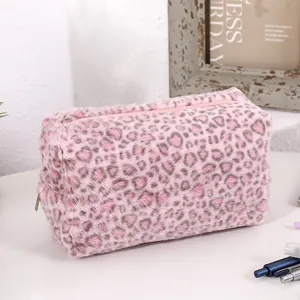 Detail of soft pink leopard print plush makeup bag with zipper closure on desk