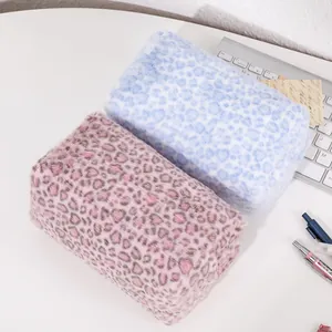 Close-up of pink leopard print plush makeup bags on a white desk with stationary