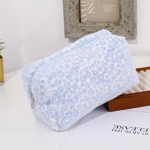 Detail of blue leopard plush makeup bag with silver metal zipper on a stylized desk