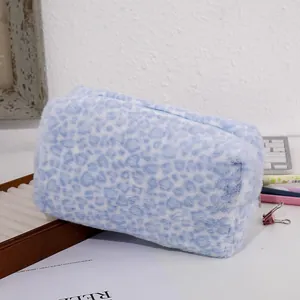 Detailed view of light blue leopard plush cosmetic bag with a zipper on a desk