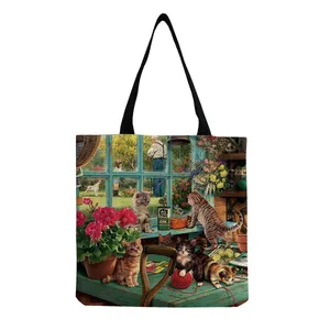 Detail of canvas tote bag featuring cute garden cat illustrations and black handles