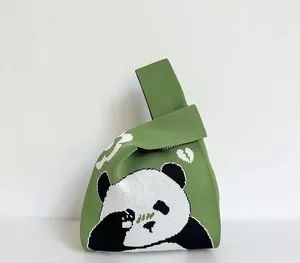 Detail of green knitted tote bag featuring a panda pattern and textured woven finish