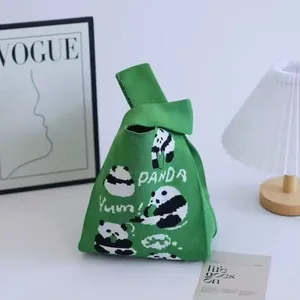 Green knit panda tote bag with Yumm text and single handle in a cozy home setting
