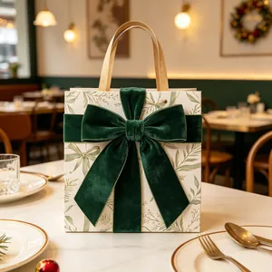 Detail of square cream gift bag with velvet green bow and elegant gold leaf prints