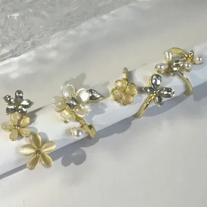 Detalle del juego de cuatro anillos de aleación dorada con perlas, cristales y flores