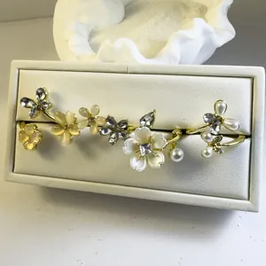 Detalle de anillos dorados de flores y mariposas con cristales y perlas en estuche blanco