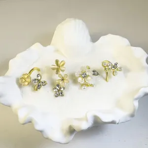 Detalle de cuatro anillos dorados con flores y mariposas en una bandeja de concha