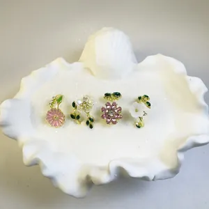 Detalle del juego de cuatro anillos de flores con esmalte y perlas en una concha