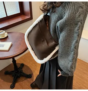 Detail view of large brown faux suede bucket bag with white plush faux fur trim detail